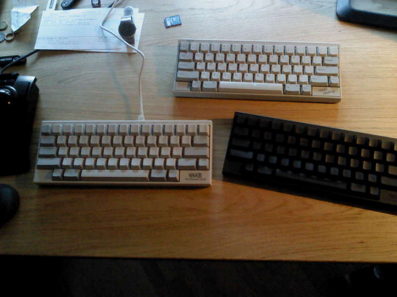 Three 60% keyboards on a desk.