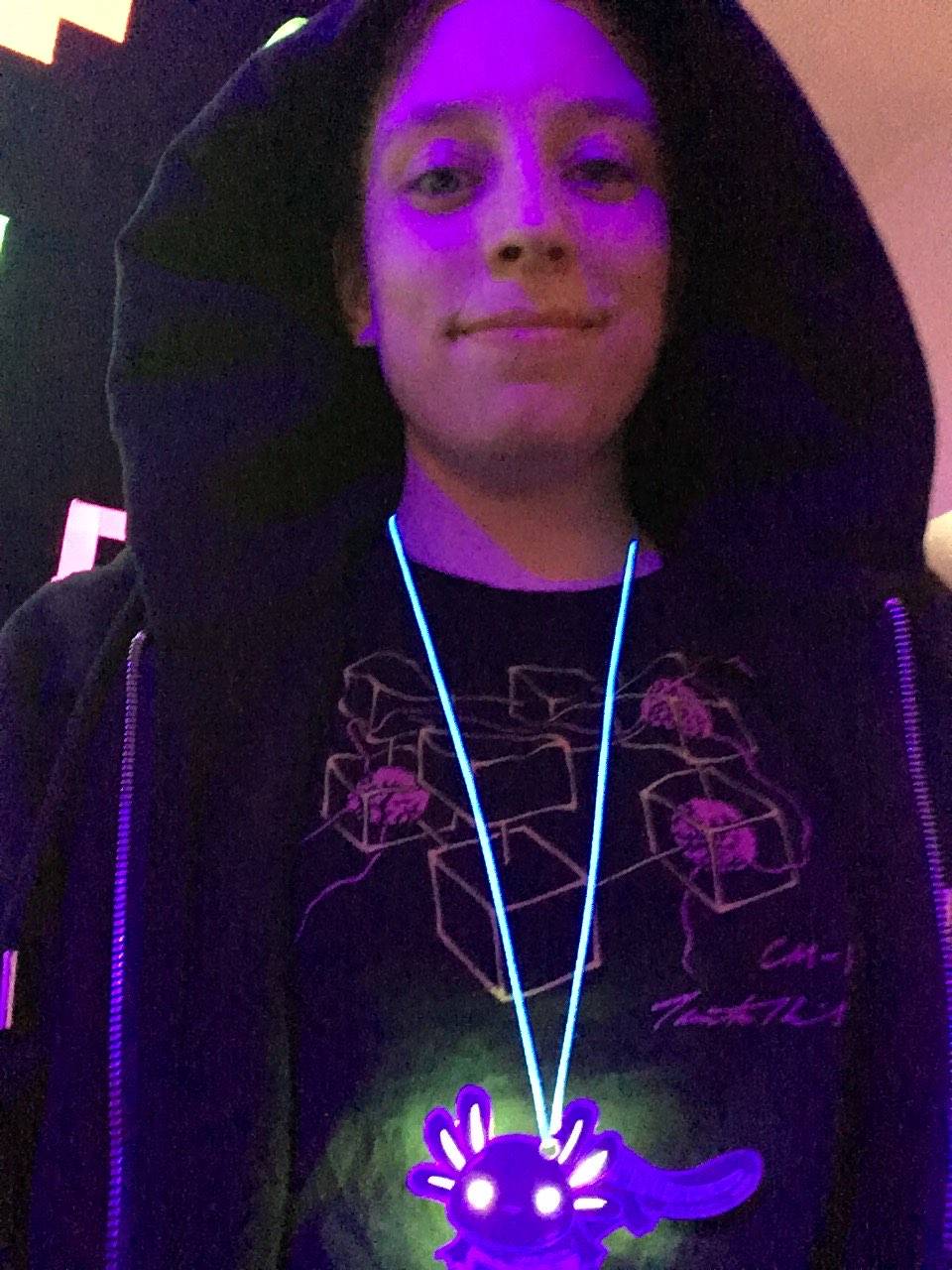 Pale kid with black hoodie, black Connection Machine t-shirt, and a shining axolotl on a strap.