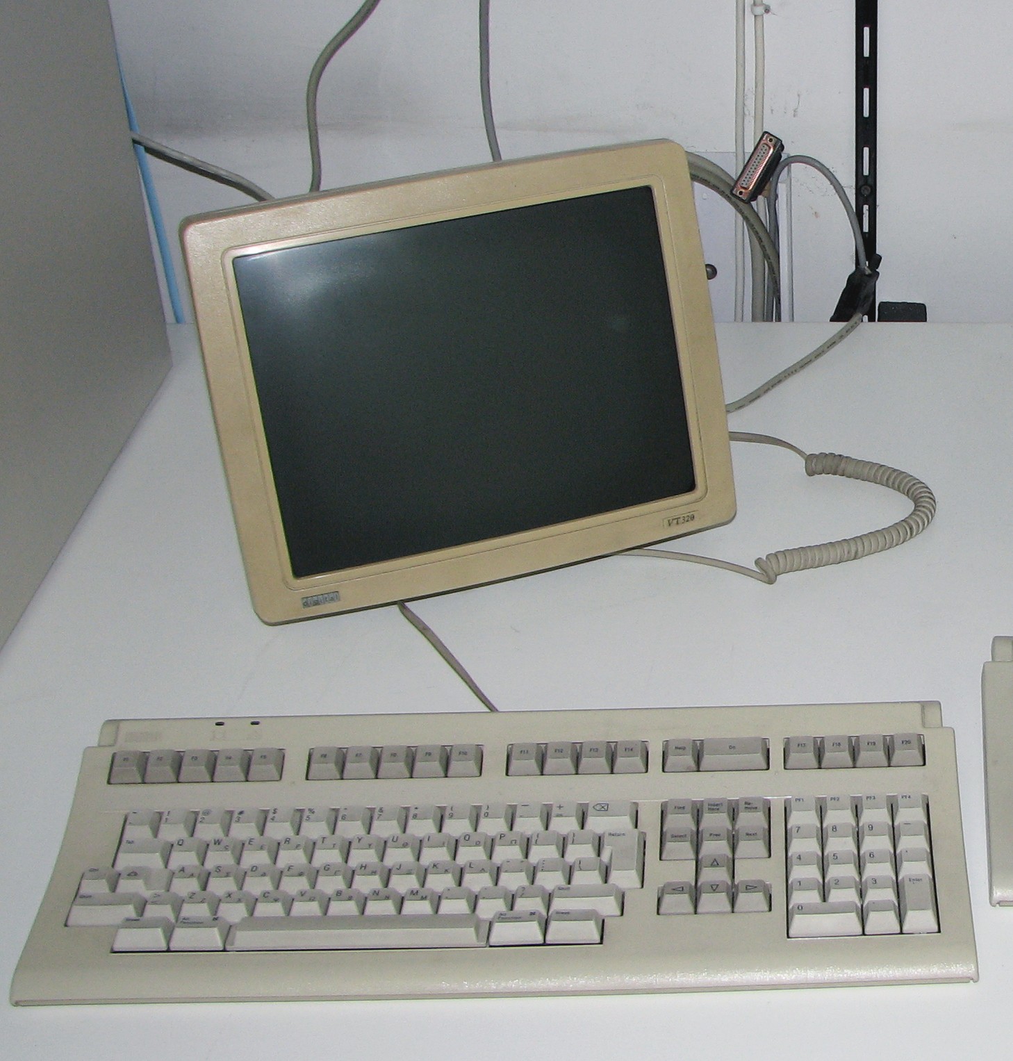 A terminal built-in to a yellowish white screen standing on a desk. Full-size keyboard in front.