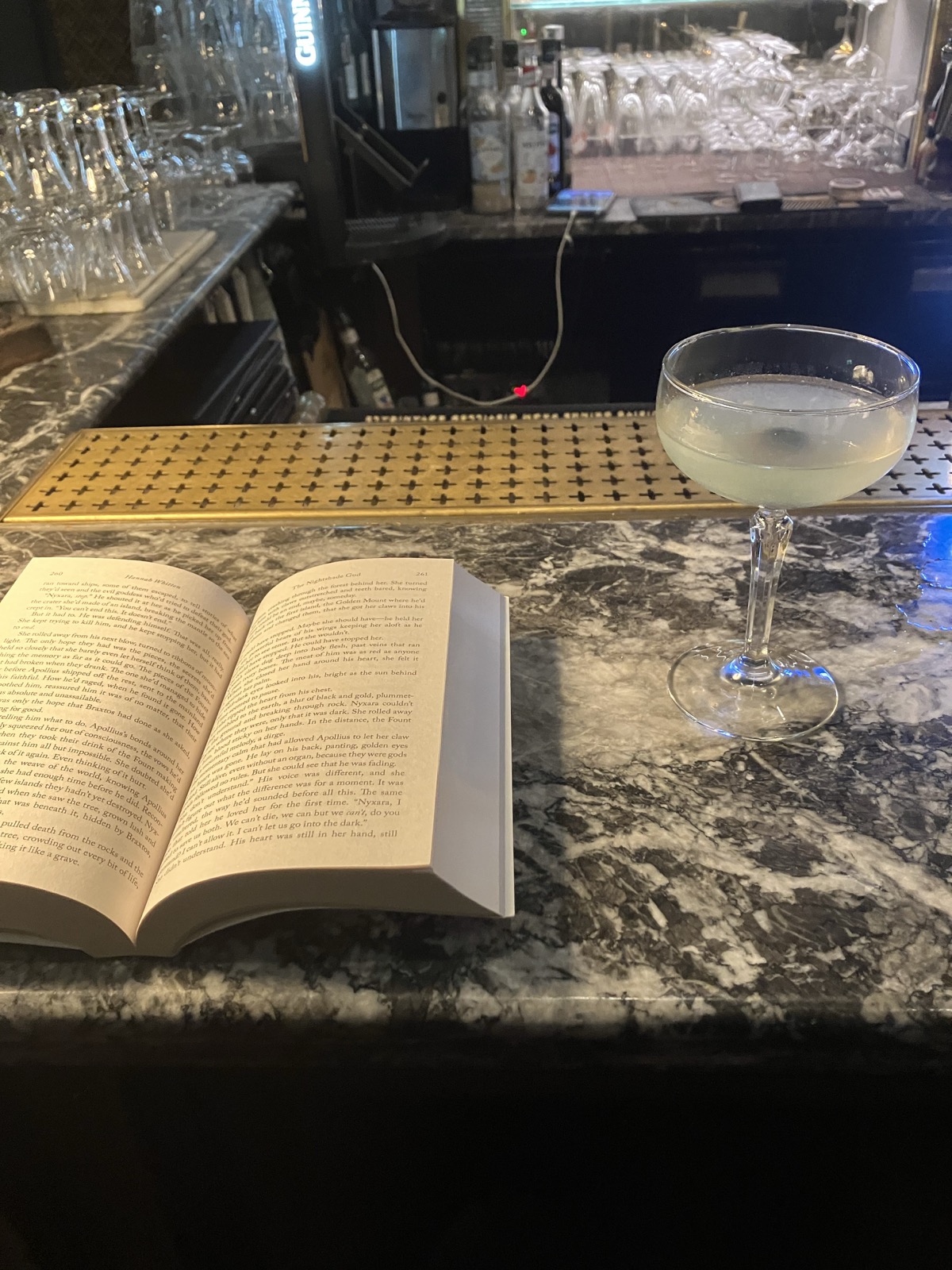 A bar disk with an open book and a cocktail glass beside it.