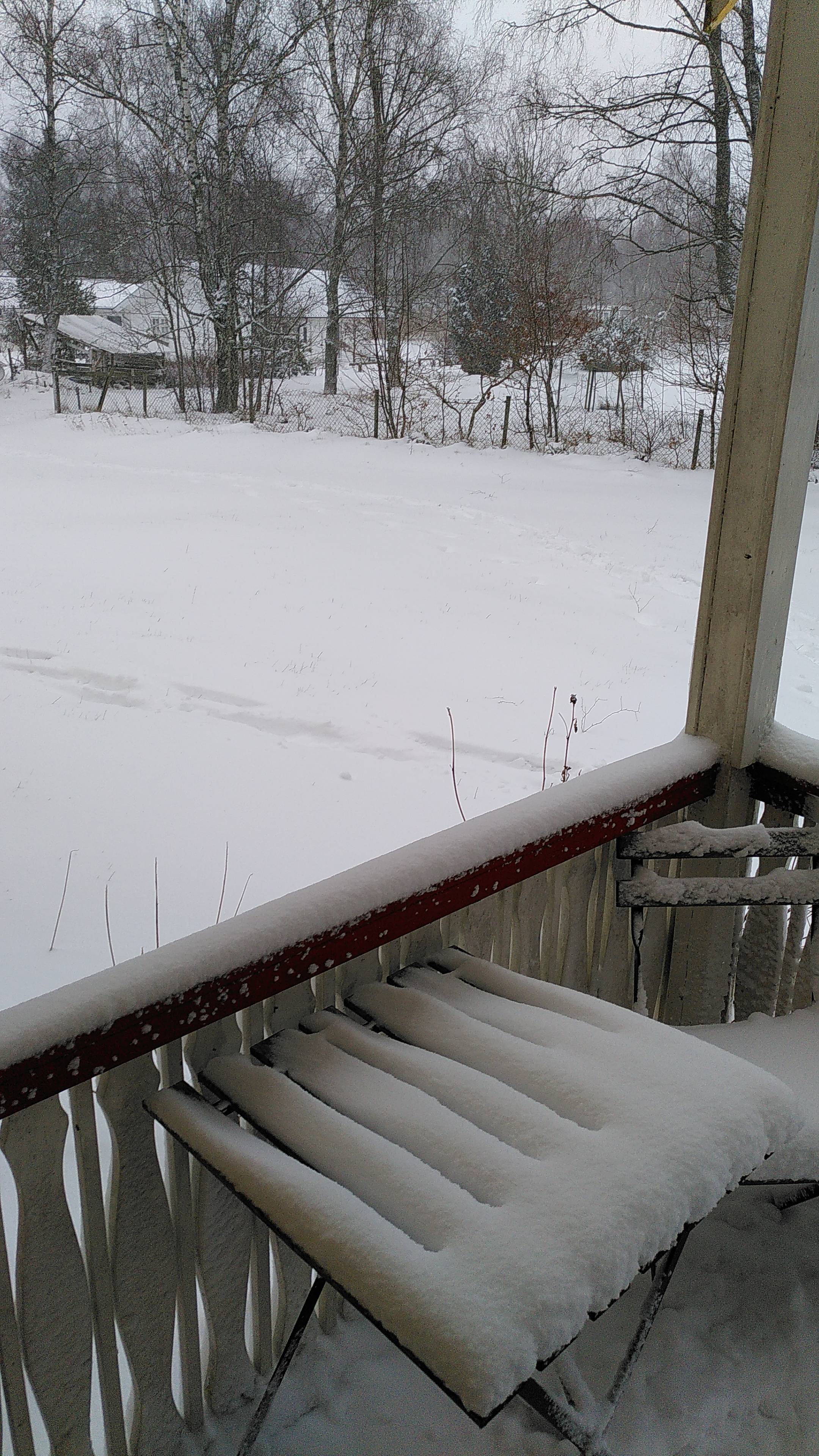 Parts of a porch and a front yard covered in a couple of cm snow.