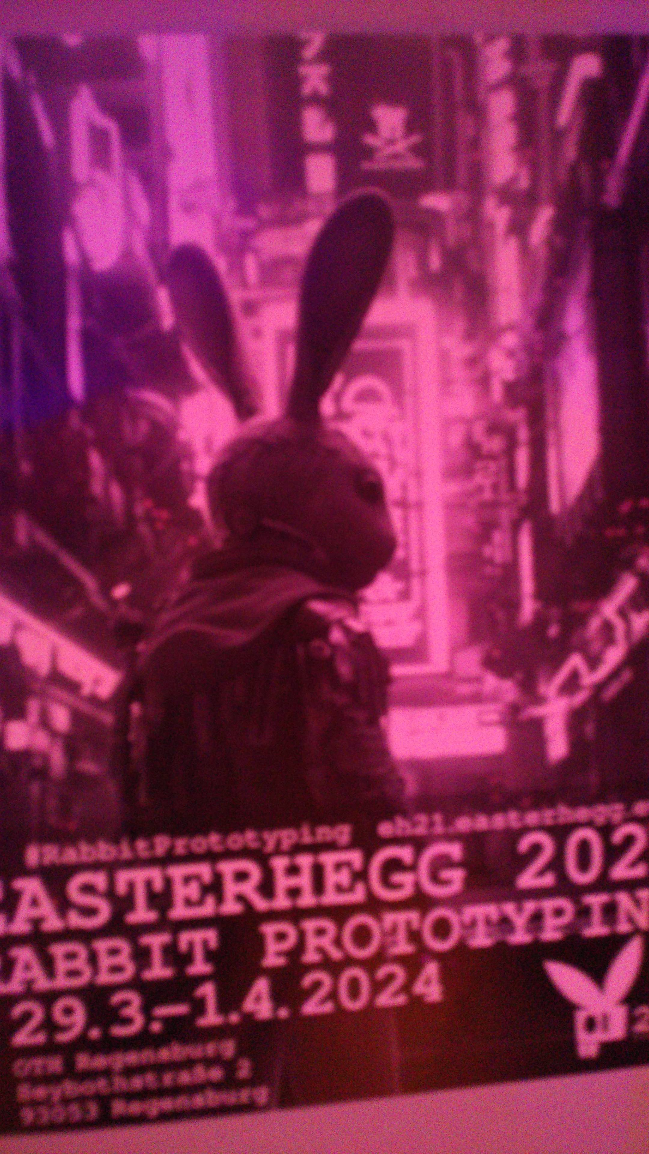 3D-style antropomorph rabbit in a cyberpunk cityscape with the text "Easterhegg 2024. Rabbit prototyping. 29.3.-1.4.2024"